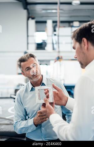 Professionals examining equipment while standing at industry Stock Photo