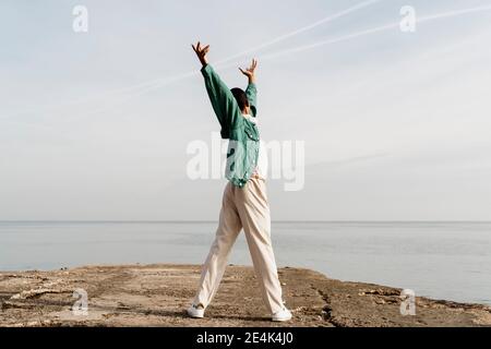 Young man dancing on pier in front of sky and sea Stock Photo