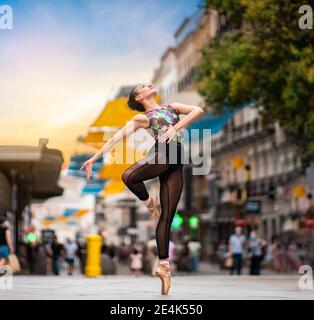 Dancer practicing ballet dancing while standing tiptoe on street in city during sunset Stock Photo