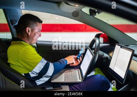 Smiling male programmer working on mobile phone in electric car Stock Photo