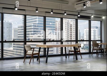 Empty wooden conference table with chairs in coworking space on downtown Stock Photo