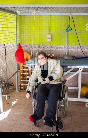 Mature disabled woman sitting on wheelchair exercising with rope at rehabilitation center Stock Photo