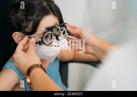 Female optometrist taking eye test of patient in clinic during COVID-19 Stock Photo