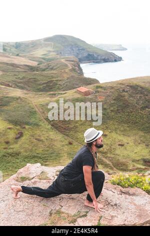 Young man doing yoga in nature on mountain at Santander, Spain Stock Photo