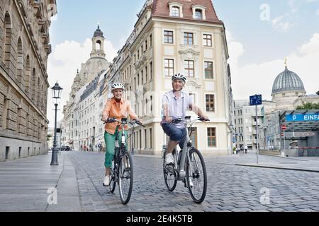 Senior tourists riding electric bicycle against Frauenkirche Cathedral at Dresden, Germany Stock Photo