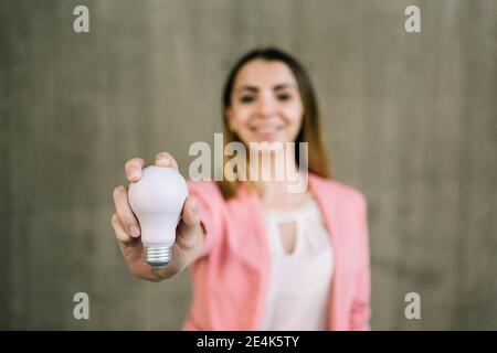 Portrait of young businesswoman holding light bulb Stock Photo