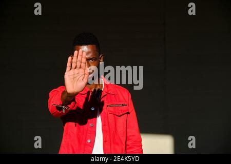 Young man in red jacket making stop gesture in sunlight Stock Photo