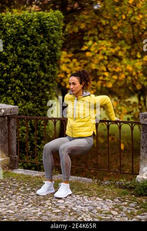 Mid adult sportswoman doing squats while exercising at park Stock Photo