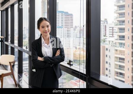 Young asian businesswoman standing crossed arm in modern office at business district Stock Photo