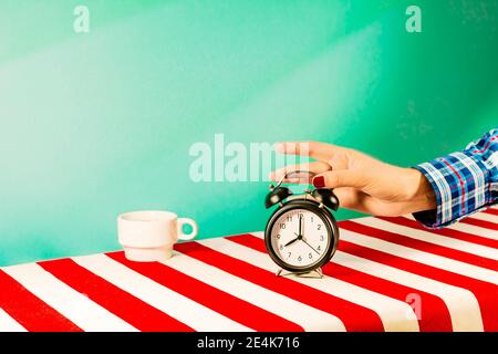 Hand of woman picking up old-fashioned alarm clock Stock Photo