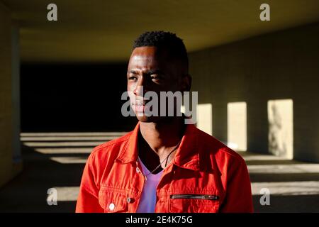 Pensive young man in red jacket outdoors Stock Photo