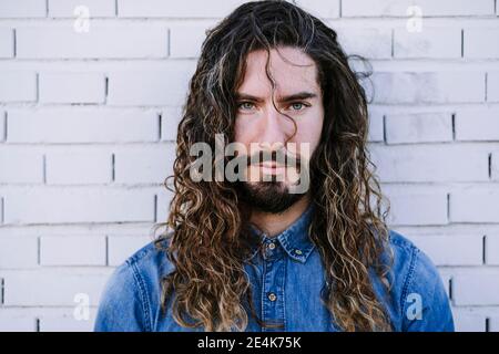 Confident young man with gray eyes against brick wall Stock Photo
