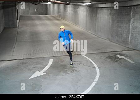 Mature man running in parking garage of residential building Stock Photo