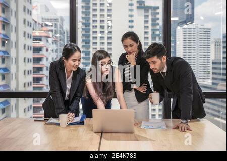 Multiethnic business team discussing and brainstorming of business plan with laptop on wooden desk at coworking space Stock Photo