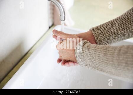 Close-up of man washing hands at sink Stock Photo