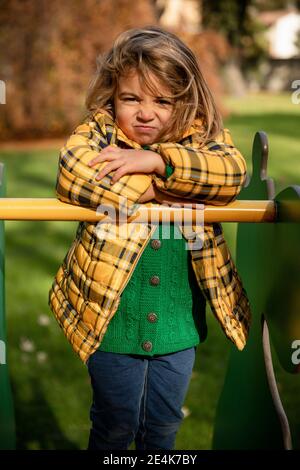 Angry girl standing with arms crossed on play equipment at park Stock Photo