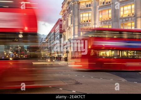 UK, London, Red double decker bus crossing Oxford Circus junction at dusk, blurred