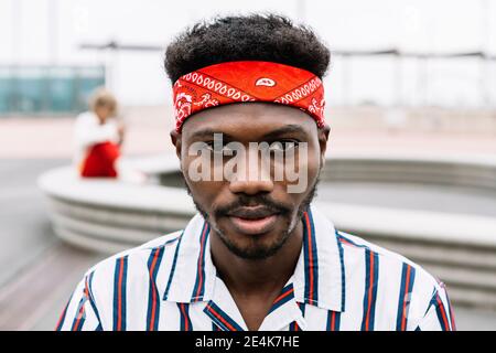Man wearing headband staring while sitting outdoors Stock Photo