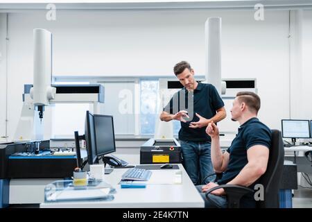 Male engineers at desk discussing in industry office Stock Photo