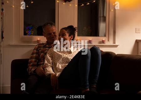 Smiling couple talking while relaxing on sofa at home Stock Photo