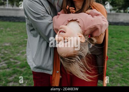 Parents holding daughter while bending back in public park Stock Photo