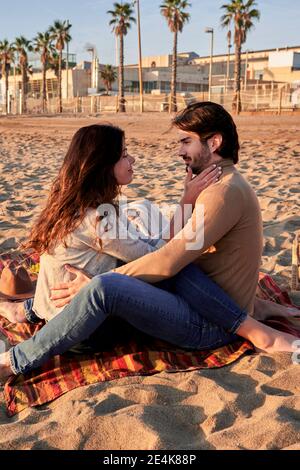 Young couple doing romance while sitting on beach Stock Photo