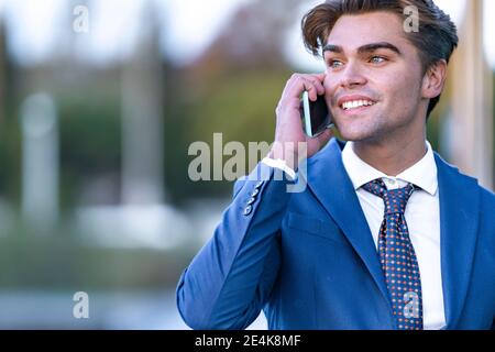 Smiling young businessman communicating on mobile phone Stock Photo