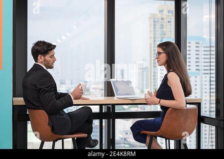 Caucasian businessperson colleague discussing and drinking on break in workplace at modern office Stock Photo