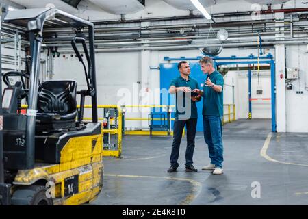 Professional male engineers communicating while working in industry Stock Photo