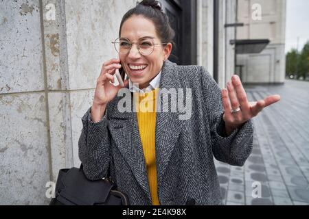 Cheerful female entrepreneur talking on mobile phone in city Stock Photo