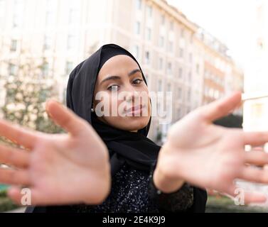 Portrait of young beautiful woman wearing black hijab gesturing toward camera Stock Photo