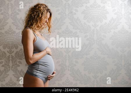 Pregnant woman with blond hair against wall at home Stock Photo