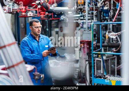 Male technician using digital tablet while working in factory Stock Photo