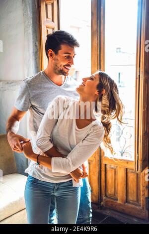 Affectionate young couple dancing at the window at home Stock Photo