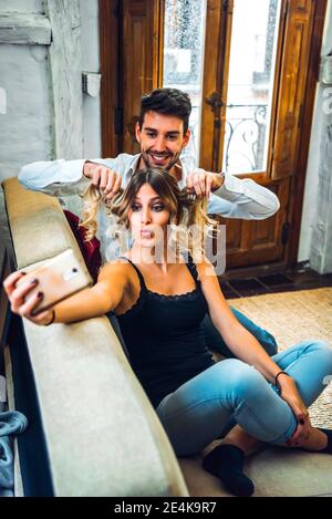 Playful young couple taking selfie on couch in living room at home Stock Photo