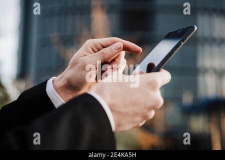 Close-up of businessman using smart phone outdoors Stock Photo