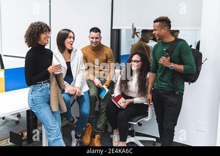 Smiling male and female professionals talking to each other at work place Stock Photo