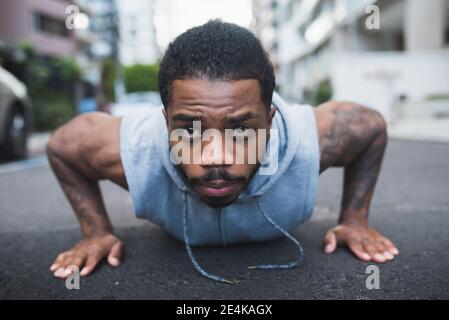 Young sportsman doing push-ups with determination on street Stock Photo