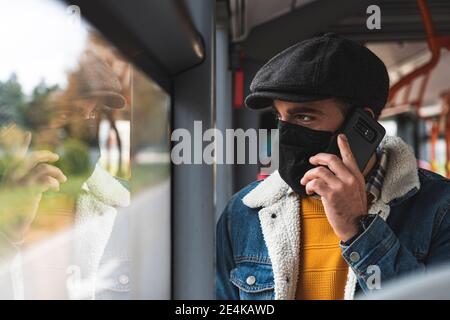 Commuter wearing protective face mask on phone call in bus Stock Photo