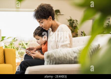 Mother and son using digital tablet while sitting at home Stock Photo