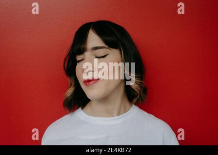 Beautiful woman with eyes closed against red background