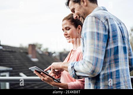 Happy mature couple using digital tablet in balcony Stock Photo
