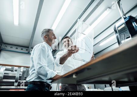 Male entrepreneurs discussing over business plan while working at industry Stock Photo