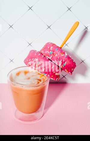 Coffee cup with pink doughnuts in spoon on kitchen table Stock Photo
