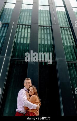 Smiling couple embracing each other against building Stock Photo