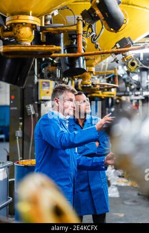 Male technicians discussing about manufacturing while working in factory Stock Photo