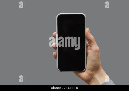 Minimal graphic background of female hand holding smartphone with black screen against gray background, copy space Stock Photo