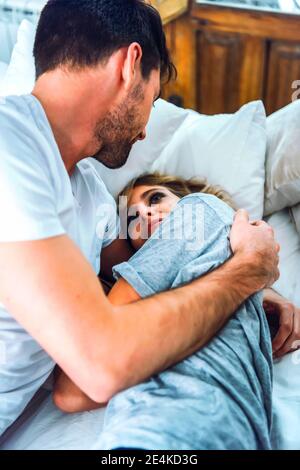 Happy affectionate young couple cuddling in bed at home Stock Photo