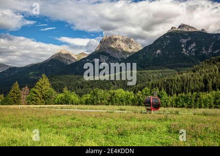 Scenic view of green forested Engadin valley with overhead cable car in foreground Stock Photo