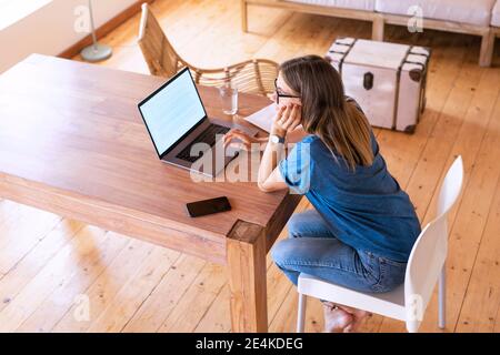 Pensive brunette female entrepreneur using laptop at home office Stock Photo